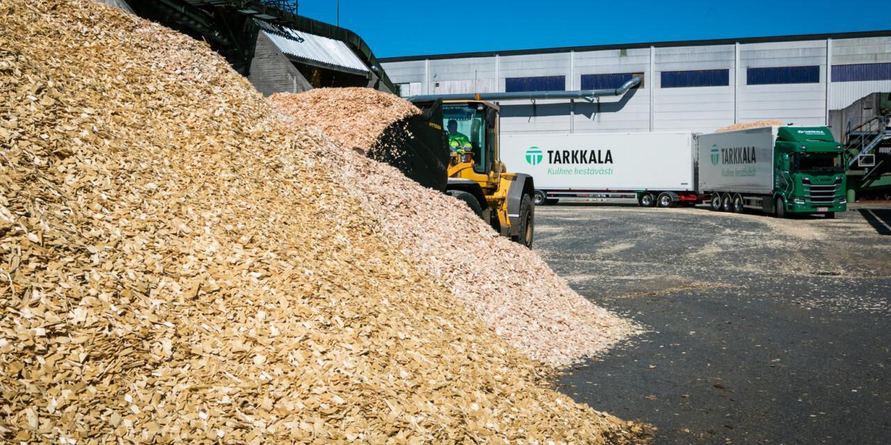 Tehdaspalvelut ulkoistettuna Tarkkalalle. Pyöräkuormaaja ottamassa kyytiin haketta. Tarkkalan rekka taustalla.